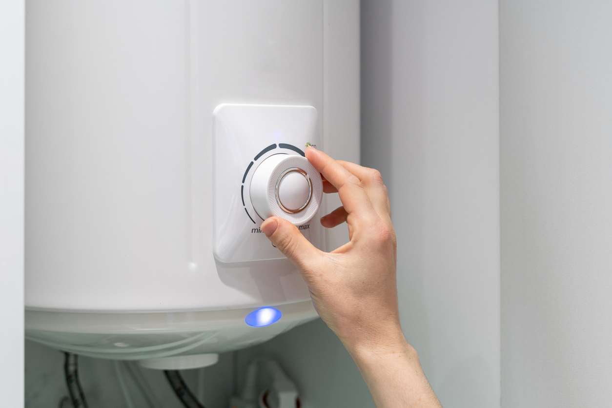 Homeowner’s hand on boiler knob, adjusting system’s temperature