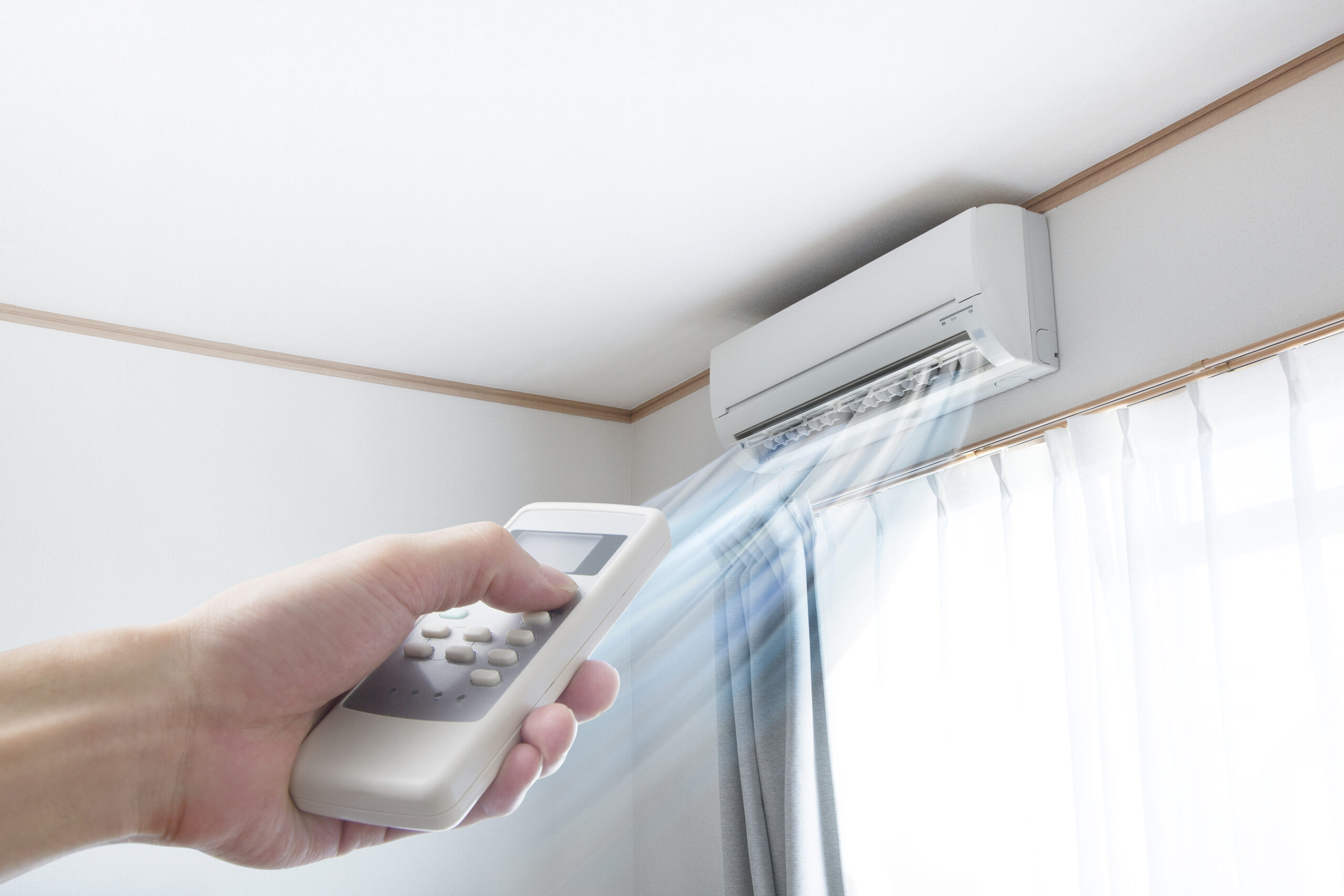 Woman's hand pointing remote at ductless mini-split blowing air
