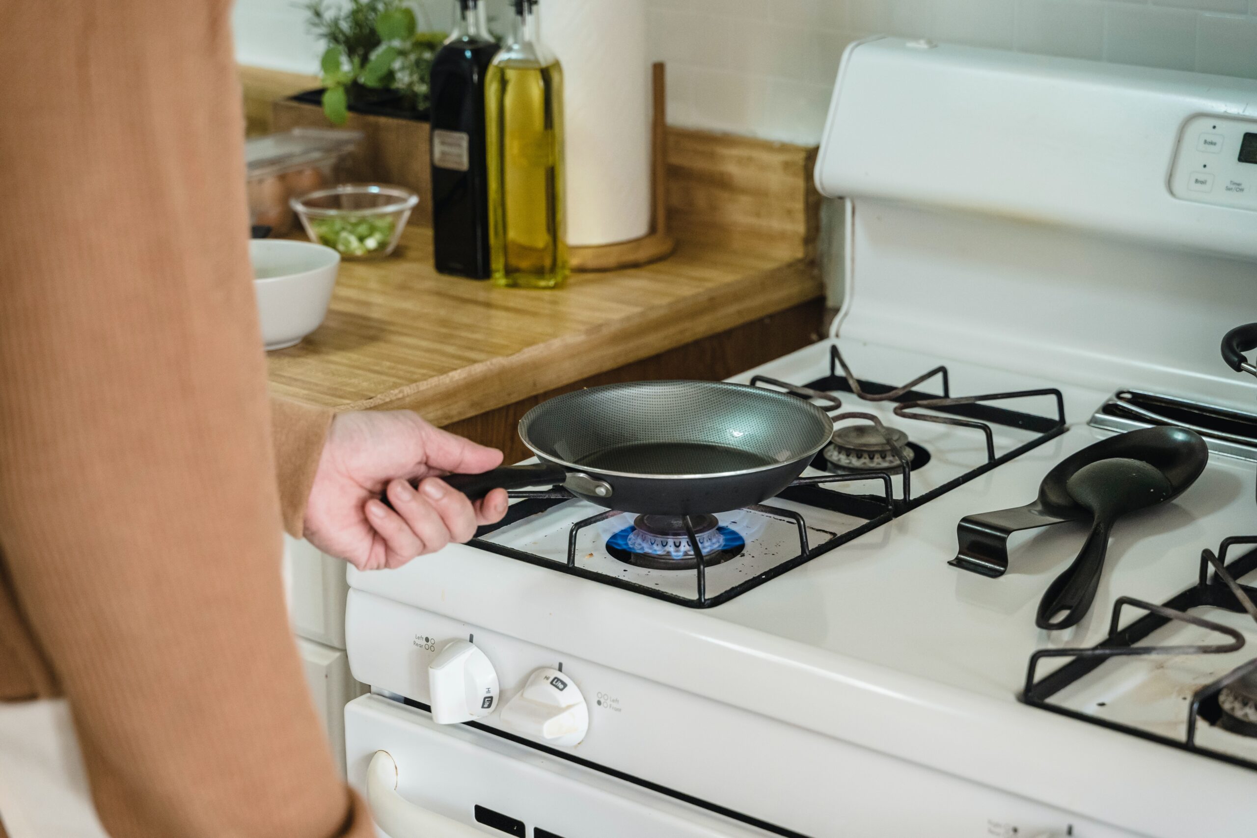 A woman putting a pan on a lit gas stove